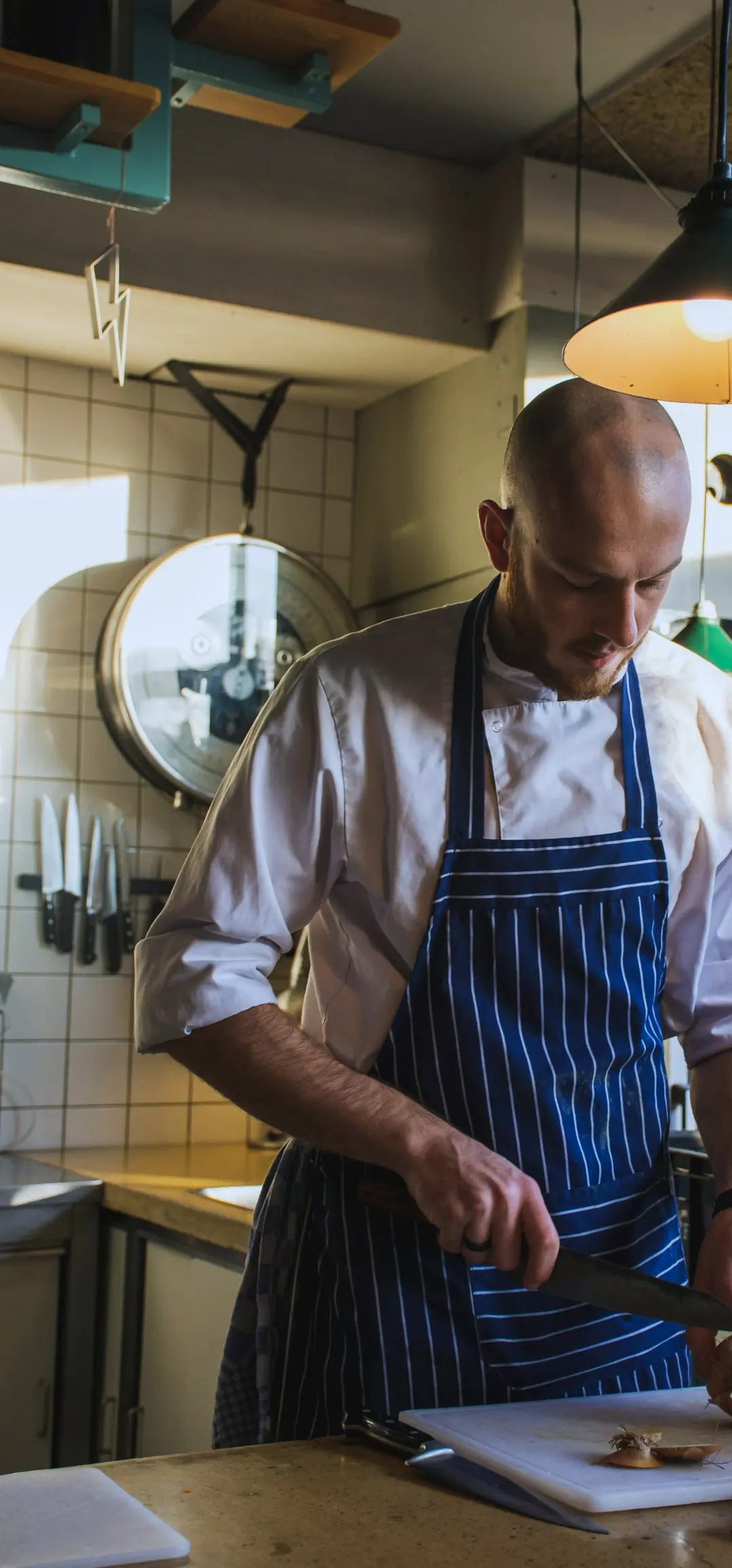 Chef in a blue and white pinstripe apron slicing on a kitchen counter
