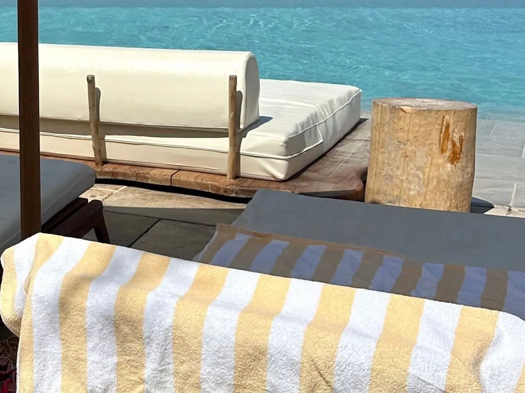 Yellow and white striped pool towels over loungers beside a resort pool