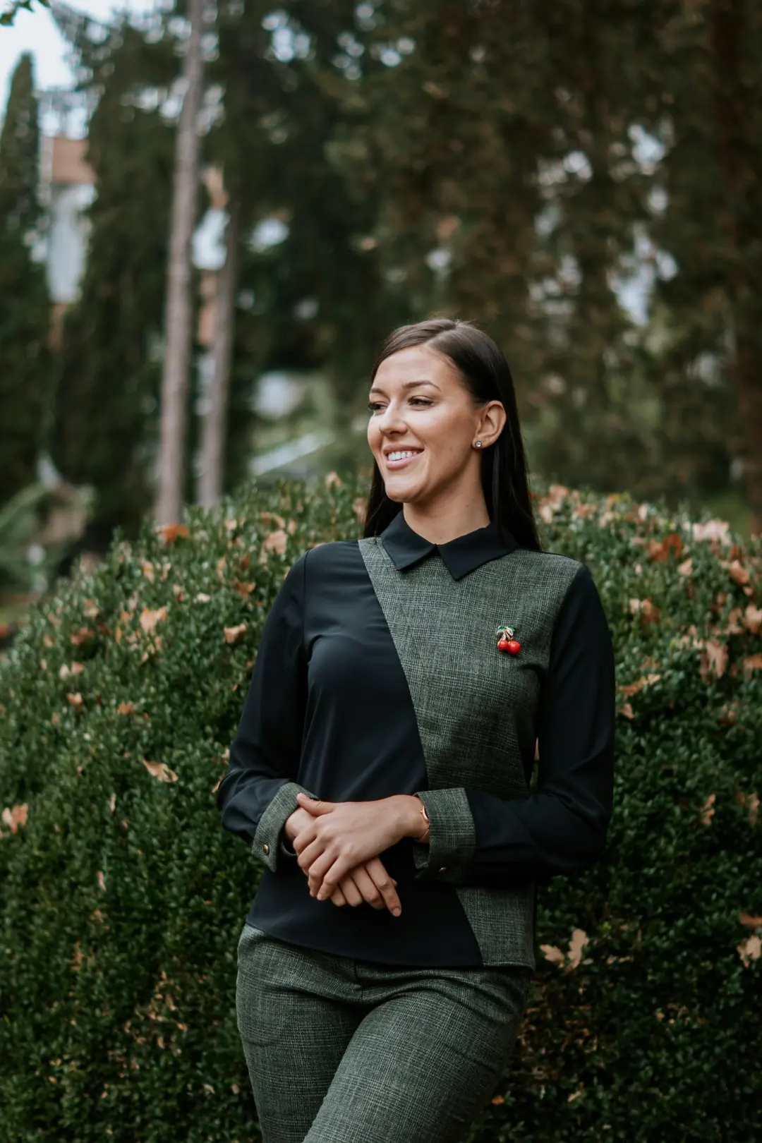 Hotel team member in a tailored uniform of black and green check cloth, standing in a garden